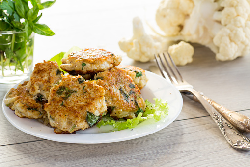 cooked vegetarian fried cauliflower cutlets, in a plate on a wooden table.