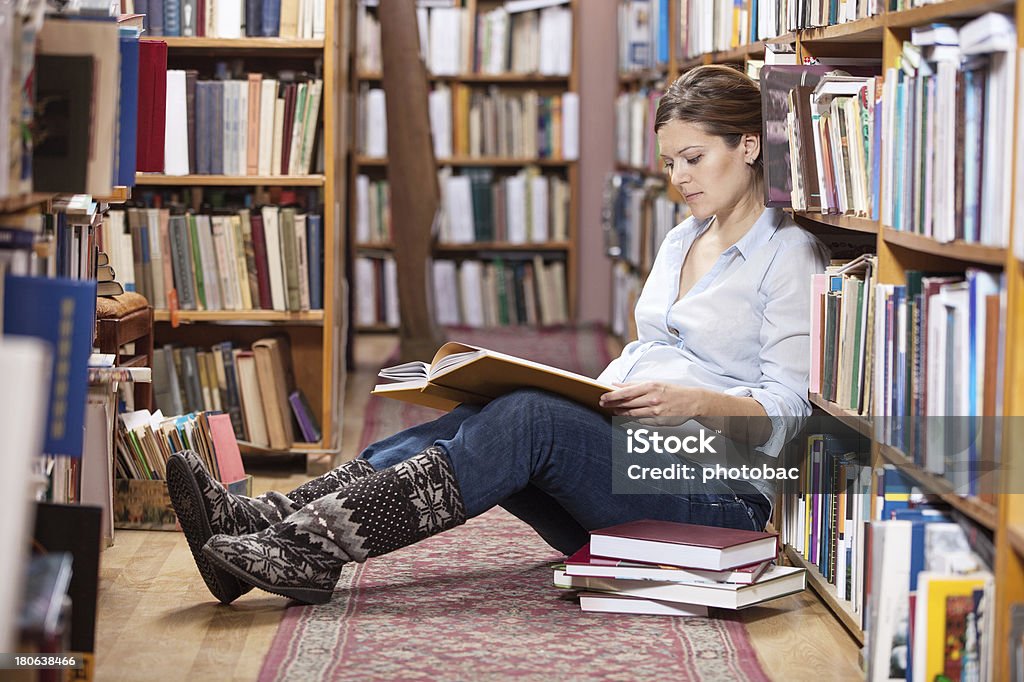 Giovane donna incinta leggendo un libro nella Libreria - Foto stock royalty-free di Incinta