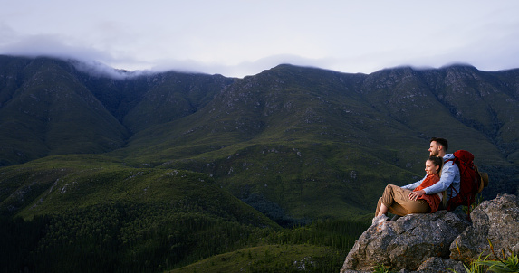 Hiking, mountain and couple in nature on rock for adventure, journey and freedom in morning. Travel, countryside and man and woman bonding, relax and explore for holiday, vacation or camping outdoors