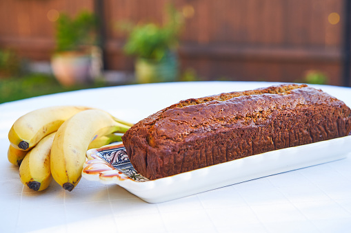 Tasty and delicious banana bread with bunch of bananas from organic farming on table of garden cake shop. Ideal dish for low carb diet or healthy lifestyle rich in fiber and with balanced nutritions.