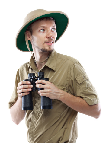 Young man wearing safari shirt and pith helmet holding binoculars, isolated on white background