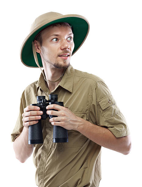 Explorer holding binoculars Young man wearing safari shirt and pith helmet holding binoculars, isolated on white background explorer stock pictures, royalty-free photos & images