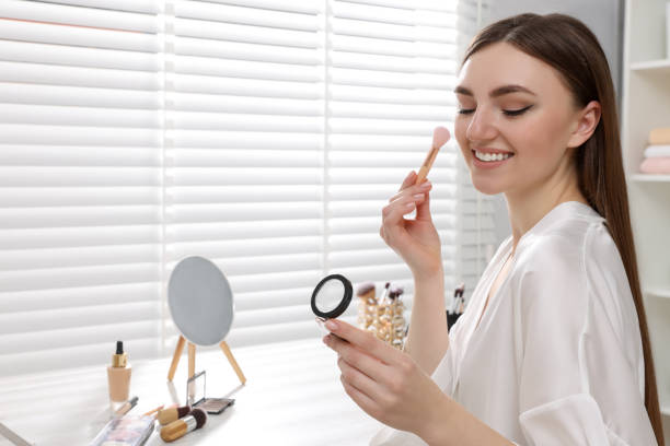 istock Beautiful young woman applying blusher with brush at dressing table indoors. Space for text 1806452960