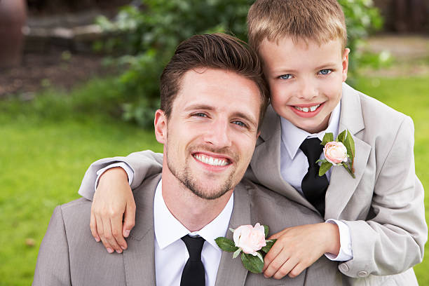 Groom With Page Boy At Wedding Groom With Page Boy At Wedding In Garden Smiling To Camera ring bearer stock pictures, royalty-free photos & images