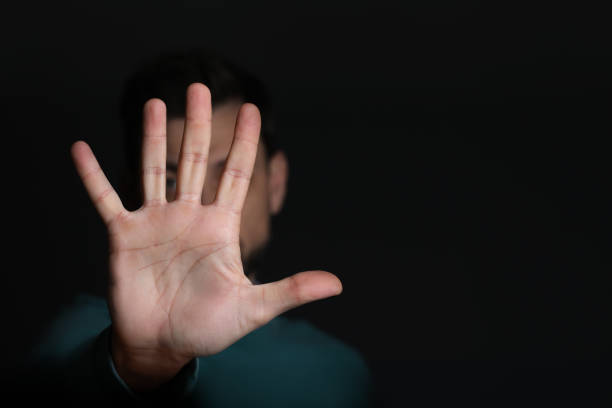 istock Man showing stop gesture against black background, focus on hand. Space for text 1806470283