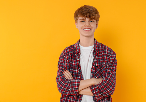 Portrait of teenage boy on orange background. Space for text