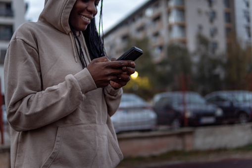 African american woman in hoodie using phone outside