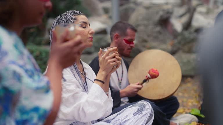 Group of multi-ethnic friends gathering in nature and having cacao tea drink ceremony