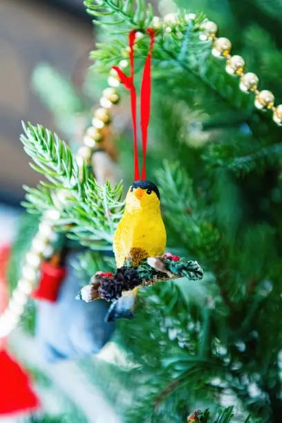 Holiday and Christmas ornaments hang from a Christmas tree