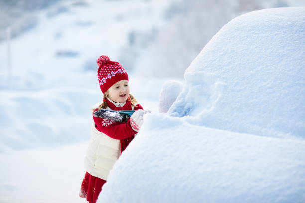 istock Child brushing off car. Kid with winter snow brush 1806509395