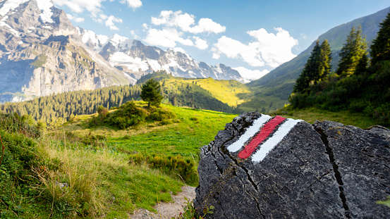 White and red trail waymark in a hiking path in the Swiss Alps with blurred background - trail signs in the Swiss Alps