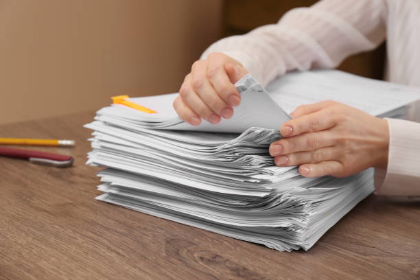 istock Woman stacking documents at wooden table indoors, closeup 1806513093