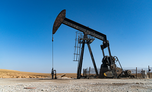 photo of oil exploration and extraction well. After the oil well is opened, oil is extracted with a horse head powered by an electric motor. The oil drilling was shot in daylight with a full frame camera.