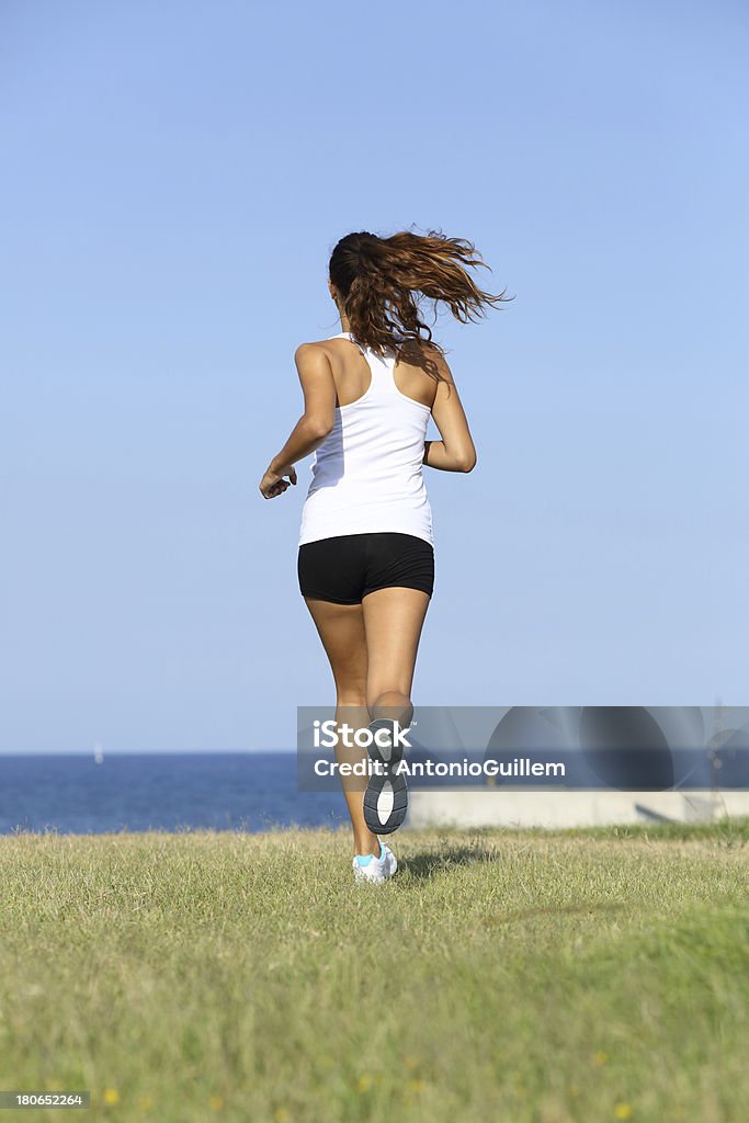 Vista posterior de joven mujer corriendo - Foto de stock de Actividad libre de derechos