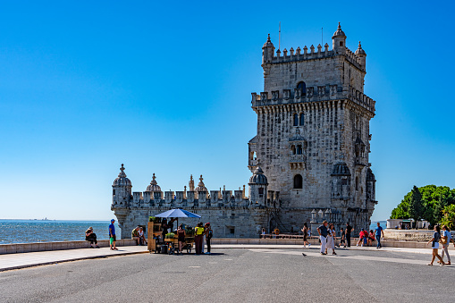 Lisbon, Portugal - Sep 29, 2023: View of Torre de Belém in summer day in the sunshine with tourists.
