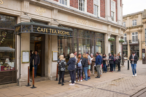 YORK, UK - April 19, 2023. People queueing outside Bettys Tea Rooms, a famous cafe in York, UK