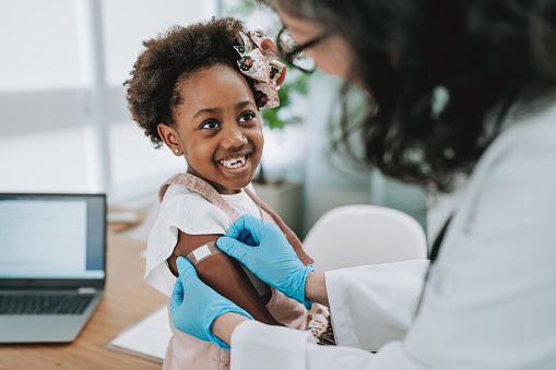 Doctor putting a bandage on the child's arm after the vaccine