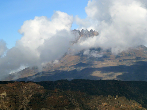 A view of the foot of the mountain and the clouds that cover the top of this mountain and the bright blue sky