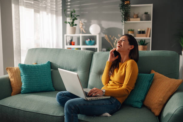 istock A woman is talking on the phone while sitting at home and using a laptop. 1806649145