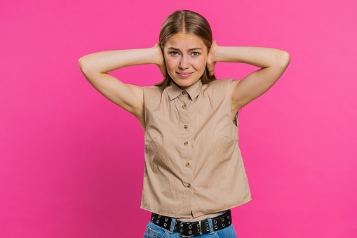 Dont want to hear and listen. Frustrated annoyed irritated woman covering ears gesturing No, avoiding advice ignoring unpleasant noise loud voices. Blonde girl isolated alone on pink background