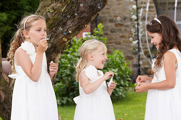 Group Of Bridesmaids Blowing Bubbles In Garden stock photo