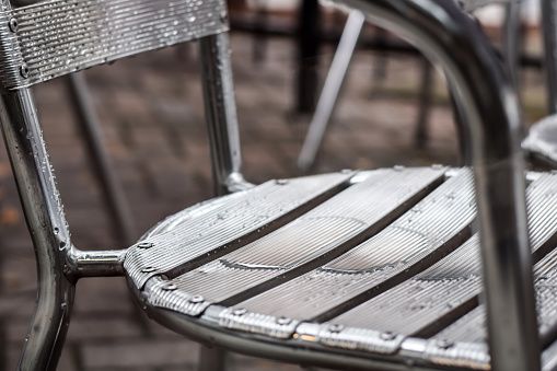 Closeup aluminum metal patio chair on a restaurant outdoor patio on a rainy day