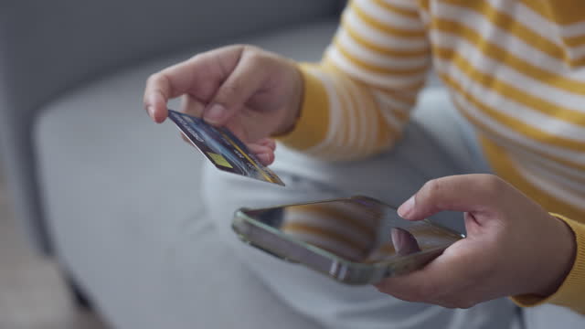 Woman shopping online using a mobile phone entering credit card number