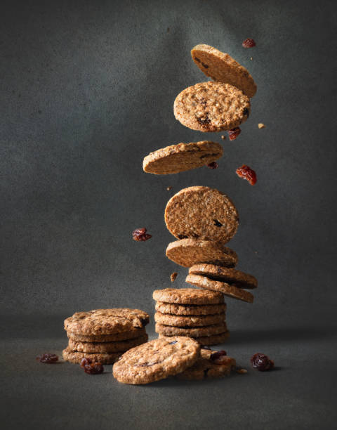 biscotti di farina d'avena con uvetta che cade in una pila su sfondo grigio - oat oatmeal isolated stack foto e immagini stock