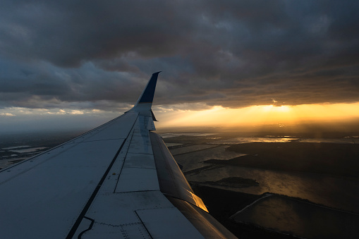 Window view of airplane wing and sunset in the horizon, Miami, Florida, USA