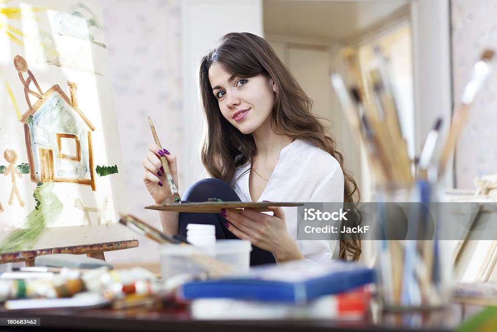 Yuong adult artist paints the house Yuong adult artist paints the house on canvas in workshop 20-24 Years Stock Photo