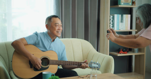 istock Relaxed mature old 60s couple using a smartphone to record video while playing guitar 1806838631