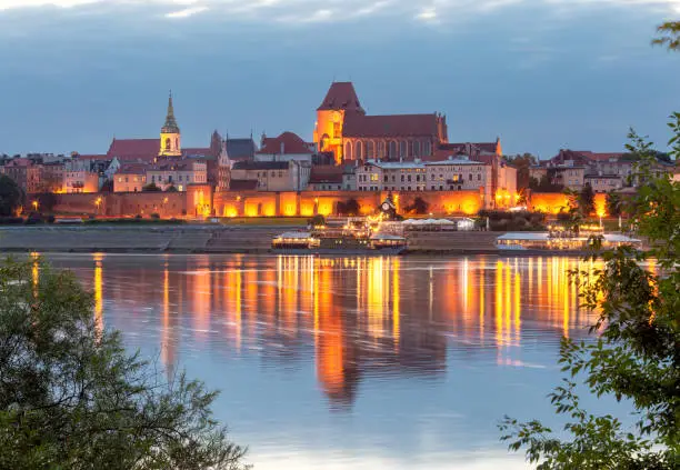 The central embankment of the city at night illumination and the river at sunset. Torun. Poland.