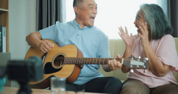 istock Relaxed mature old 60s couple using a smartphone to record video while playing guitar 1806845125