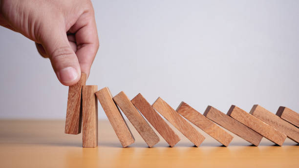 istock Businessman hand stopping falling blocks on table, stopping the domino effect concept for business solution, strategy and successful intervention. 1806860608