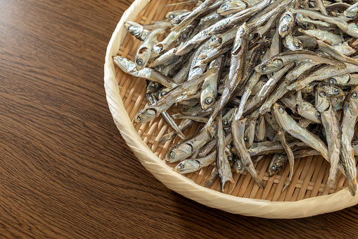 A pile of dried sardines on a bamboo colander