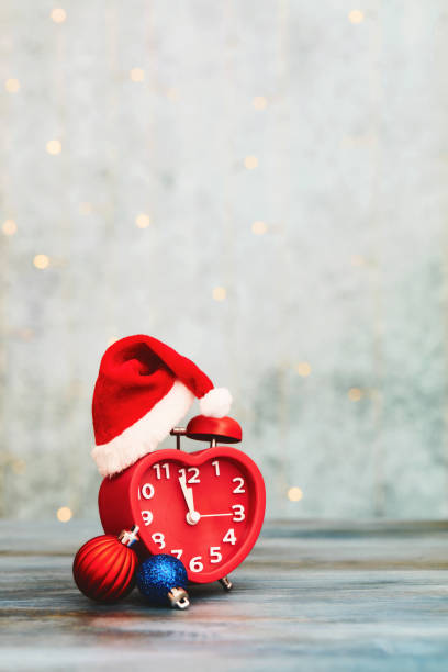 istock Red alarm clock wearing a Santa hat with Christmas decorations and copy space. Christmas time 1806922085