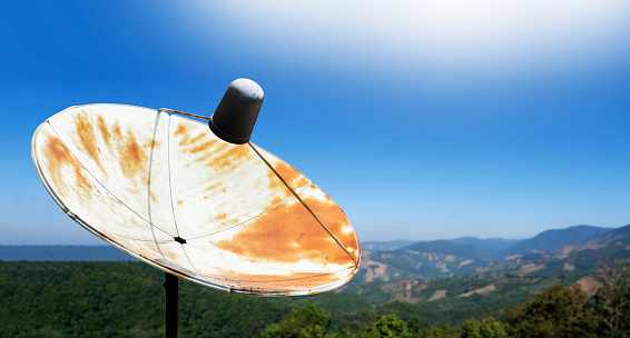 An old c-band satellite dish installed on the mountain in remote areas of Asian countries to receive tv and radio signal from sattellite station in the city.