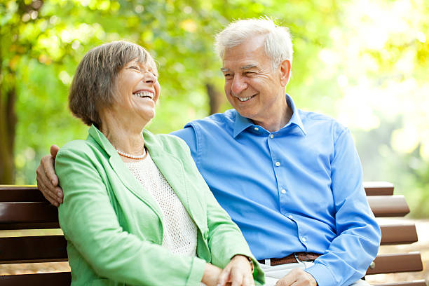 Senior couple enjoying time together at the park Senior couple enjoying time together at the park senior adult women park bench 70s stock pictures, royalty-free photos & images