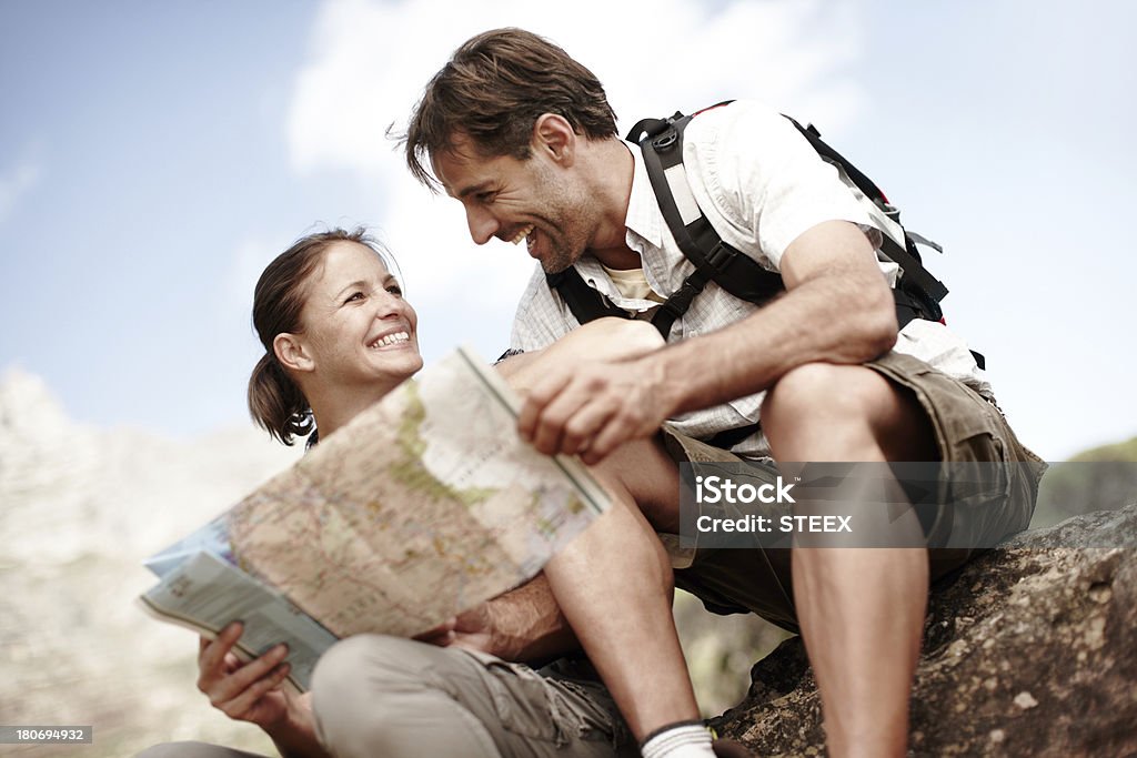 Which way should we go next? Two hikers consulting their map while sitting on a mountain top Hiking Stock Photo