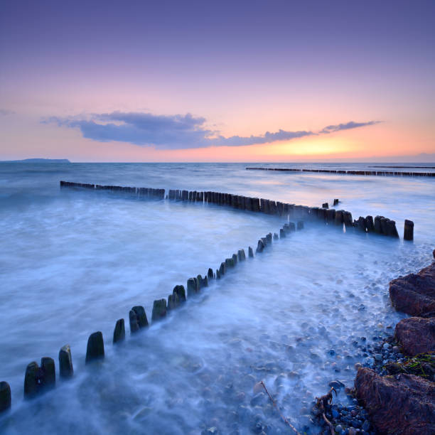 stary breakwater na plaży o zachodzie słońca - beach sunrise waterbreak sea zdjęcia i obrazy z banku zdjęć