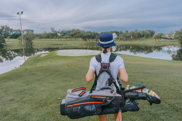 istock rear view female golfer walking toward golf course 1806953397