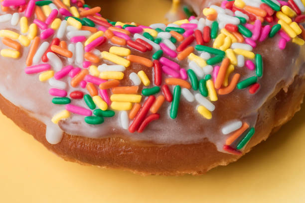istock Vanilla Frosted Rainbow Sprinkle Donut on a Yellow Background 1806955155