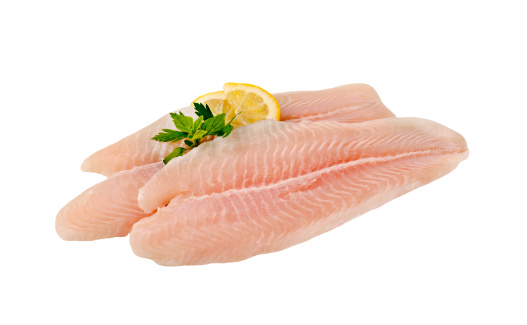 raw pollock fillets with lemon slice and parsley on a white background