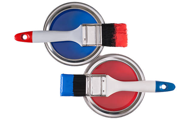 Two paintbrushes on tins of blue and red paint