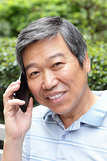 istock old man laughing and smiling with a smart phone 180697436