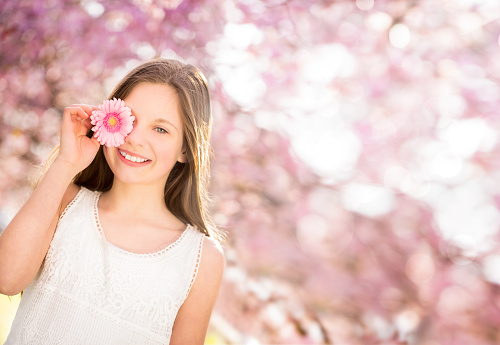 close-up portrait of a smiling blonde woman in a blossoming garden in spring, selective focus