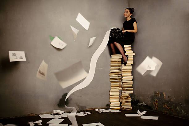 Surreal writer "Young woman sitting on the books and typing, toned image" author stock pictures, royalty-free photos & images