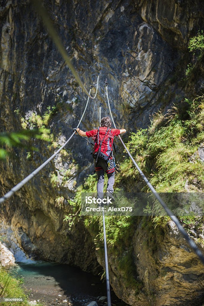 Climber on a Rope Bridge Climber cross a rope bridge on a via ferrata (klettersteig) Dolomites Stock Photo