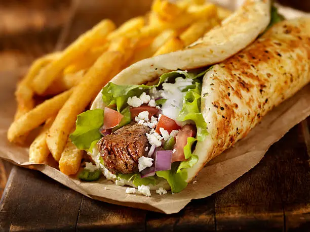 "Beef Souvlaki Pita Wrap with Lettuce, Tomatoes, Red Onions, Feta Cheese, Tzatziki Sauce and a Side of french Fries -Photographed on Hasselblad H3D-39mb Camera"