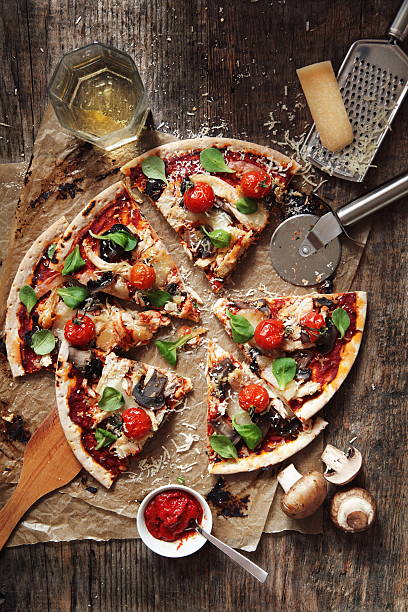 Pizza "Domestic pizza with cherry tomatoes, poultry, mushrooms, corn salad and cheese on wooden table." pizza cutter stock pictures, royalty-free photos & images